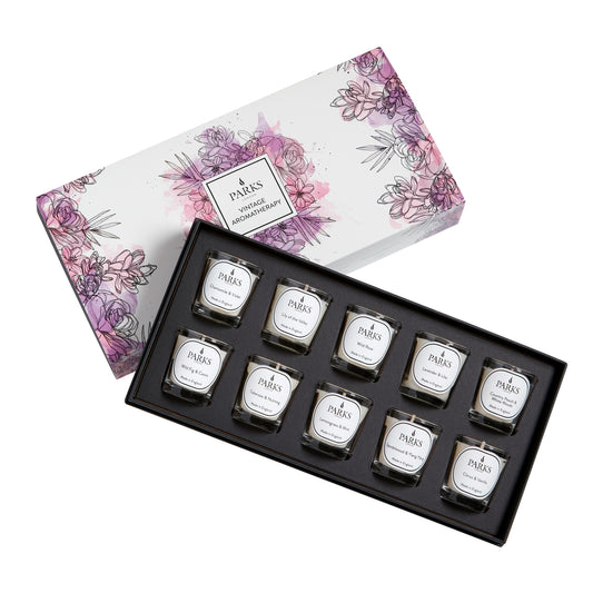 Set of small candles in a decorative box with floral design on the lid.